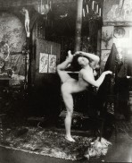 Nude balancing on her right foot holding her left foot above her head with her left hand