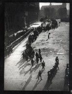 A procession of men through a Paris street (seen from above) with deep shadows cast from top right to bottom left