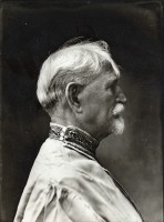 Mucha dressed in a traditional Czech shirt with head and shoulders seen in profile against a dark background