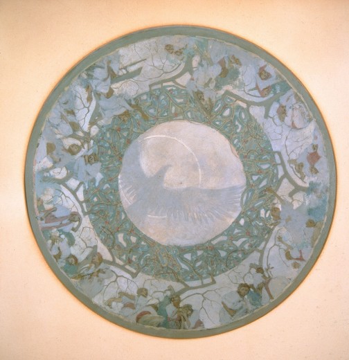 A circular frieze with figures around the outer edges, a stylised plant pattern in the middle, and a bird with open wings in the centre