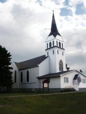 Pisek Church, North Dakota A white church and spire with green grass in front and grey clouds behind