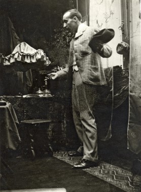 Gauguin in Mucha's studio A full-length black and white photograph of Gauguin in profile holding a hat