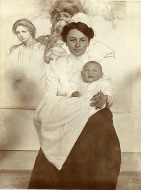 Maruška with Jiří as a baby Maruška holding a baby in front of one of Mucha's drawings