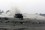 Fighting between Insurgents and Coalition forces in Iraq A tank emerges through a cloud of dust onto a deserted landscape scattered with debris