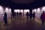 Visitors look at small works lit by spotlights in a dark mauve room